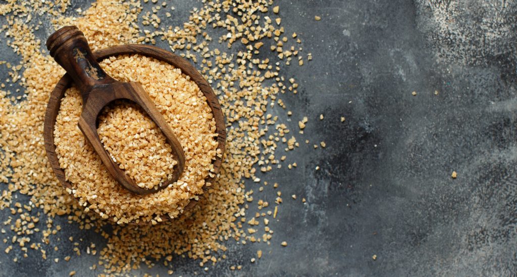 kasza bulgur w drewnianej misce i rozsypana na stole
