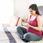 Kobieta w ciąży je sałatkę z orzechami