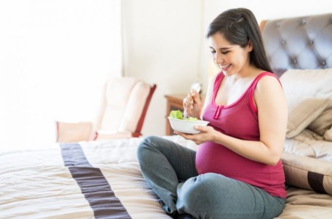 Kobieta w ciąży je sałatkę z orzechami