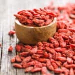 jagody goji w drewnianej misce i rozsypane na stole