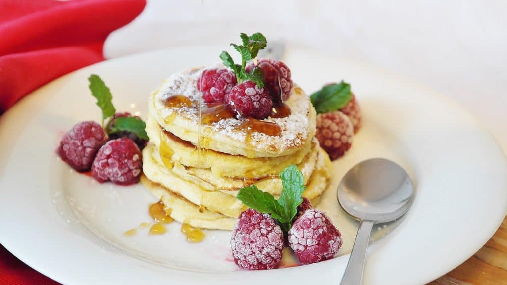 Pancake zrobiony z mąki migdałowej przyzdobiony świeżymi malinami i liśćmi mięty