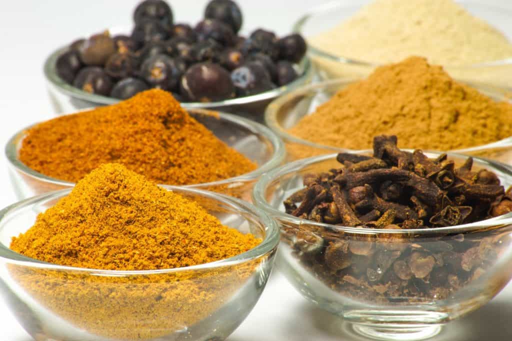 Przyprawy w szklanych miskach: curry, kurkuma mielona, cynamon, goździki i inne