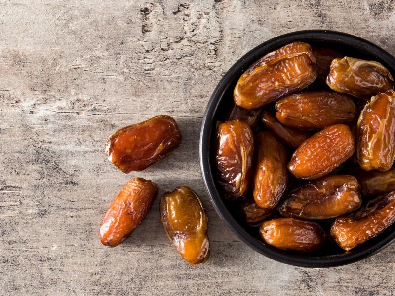 Widok z góry na daktyle w ciemnej misce i wysypane na stół