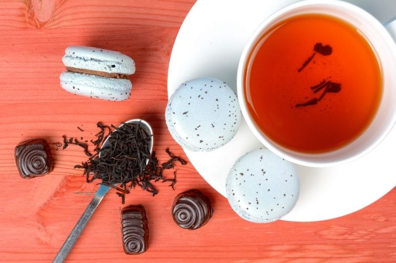 Zaparzona herbata Earl Grey w filiżance, obok znajdują się różne słodycze