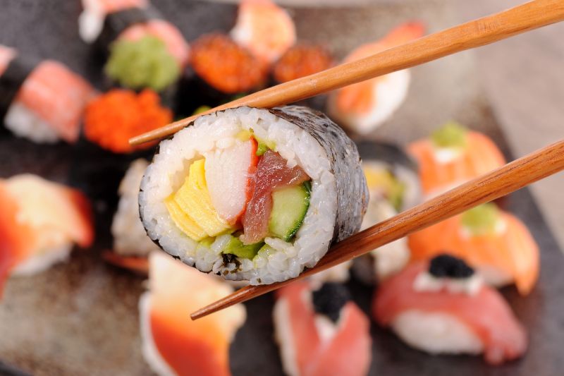 Zbliżenie na sushi pomiędzy pałeczkami