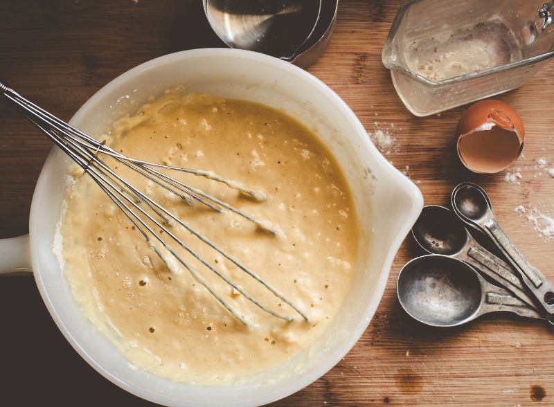 Biała miska z ciastem na naleśniki, obok narzędzia kuchenne
