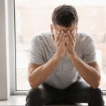 Przygnębiony mężczyzna siedzący z twarzą ukrytą w dłoniach