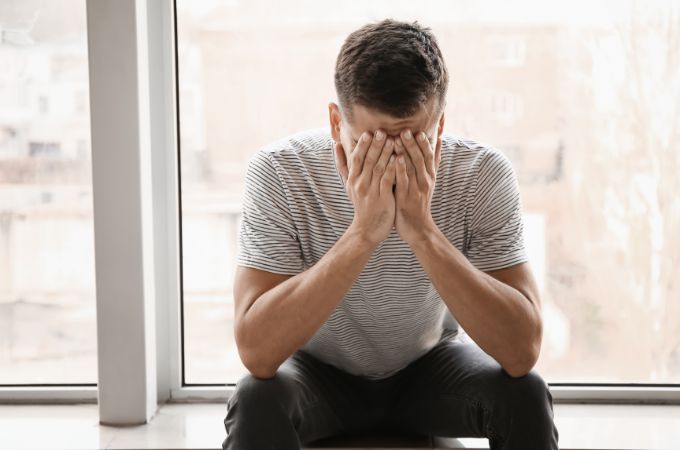 Przygnębiony mężczyzna siedzący z twarzą ukrytą w dłoniach