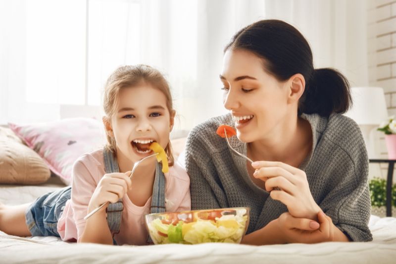 Mama z córką jedzą sałatkę z dodatkiem oleju z czarnuszki