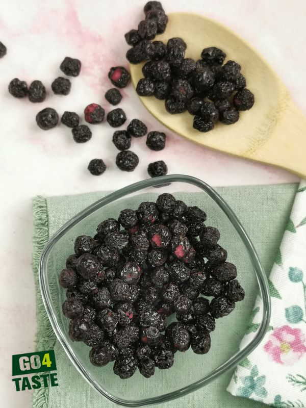 Aronia liofilizowana w szklanej misce i rozsypana na stole