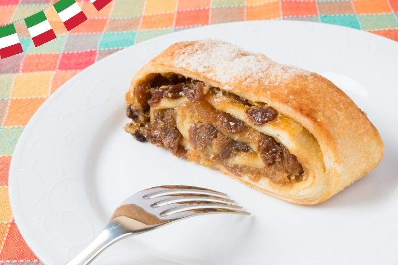 Zbliżenie na strudel jabłkowy z orzechami piniowymi na białym talerzu