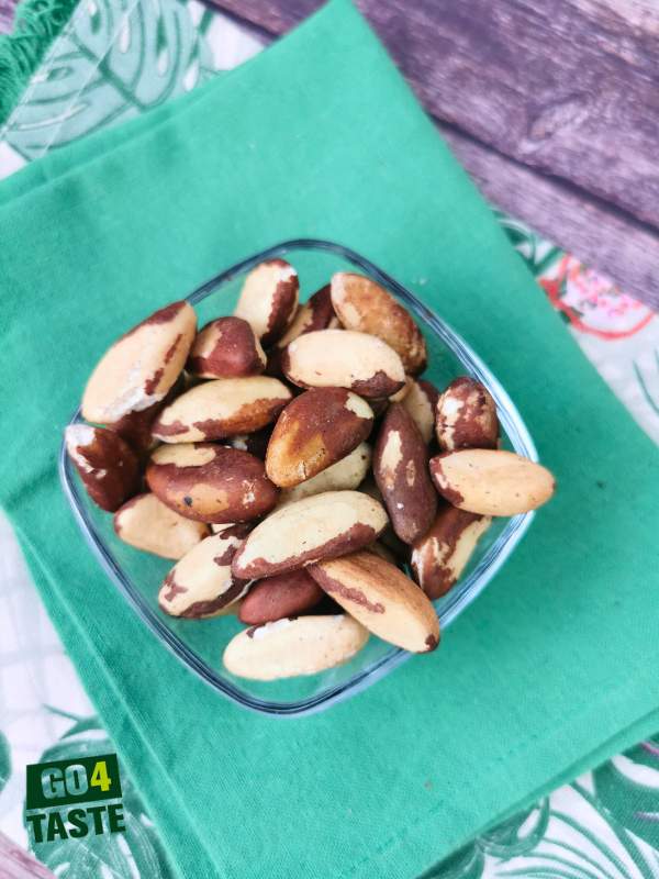 Orzechy brazylijskie w szklanej miseczce położone na zielonej ścierce