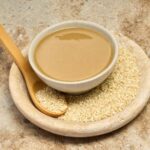 Pasta tahini w miseczce obok nasion sezamu