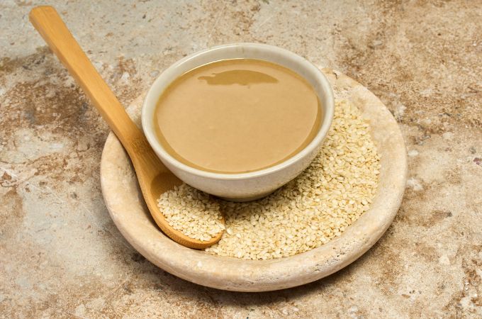 Pasta tahini w miseczce obok nasion sezamu